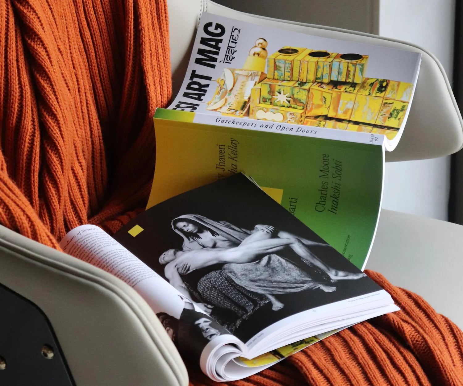 Open book with visible text and images on a chair with orange fabric